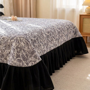 Gros plan sur le matelassage boutis et le volant froncé noir du couvre-lit