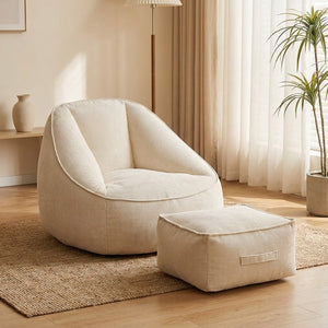 Fauteuil pouf en velours côtelé crème avec repose-pieds près d'une fenêtre lumineuse