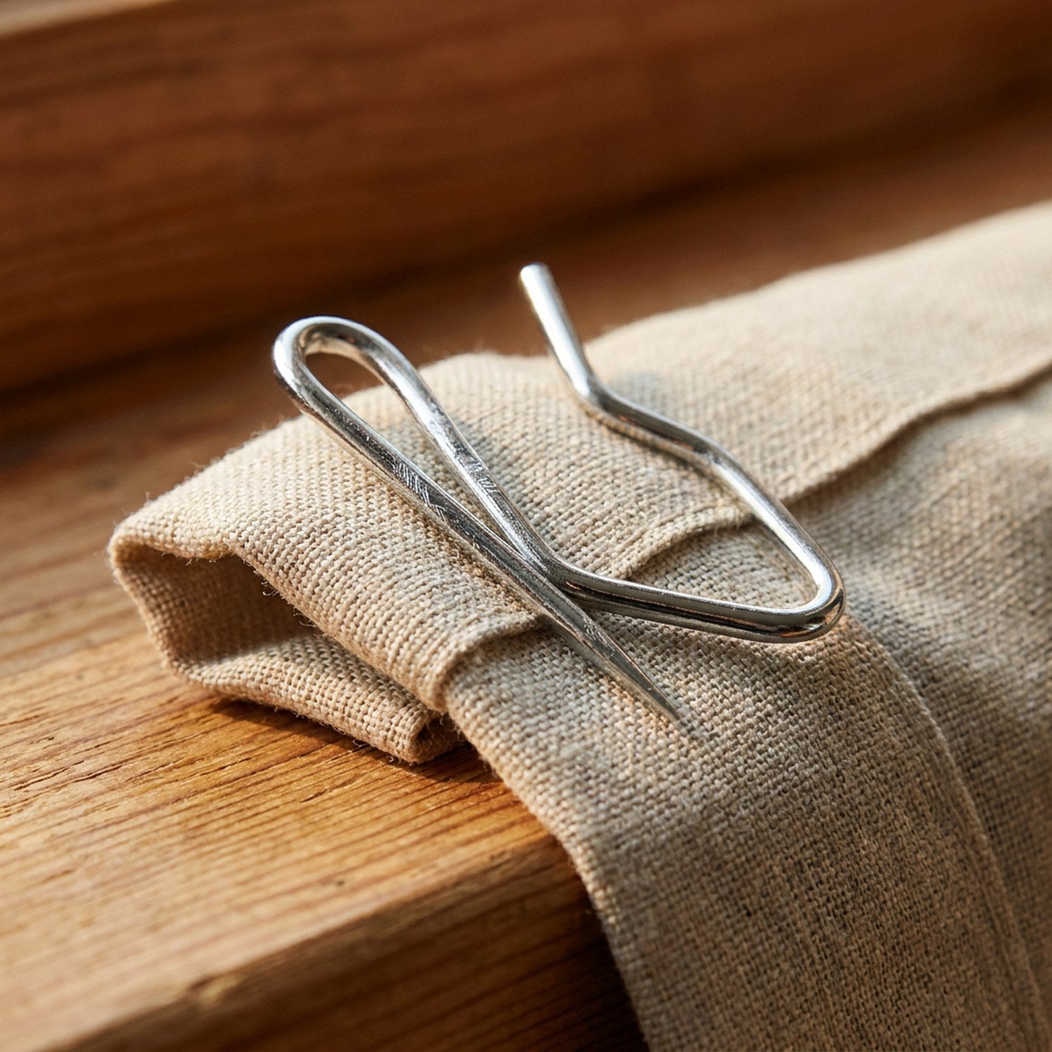 Détail macro d'un crochet de rideau en métal pincé dans un pli de tissu