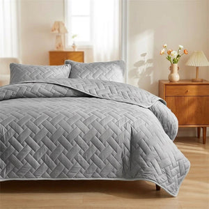 Couvre-lit matelassé gris à motif de tissage géométrique sur un lit