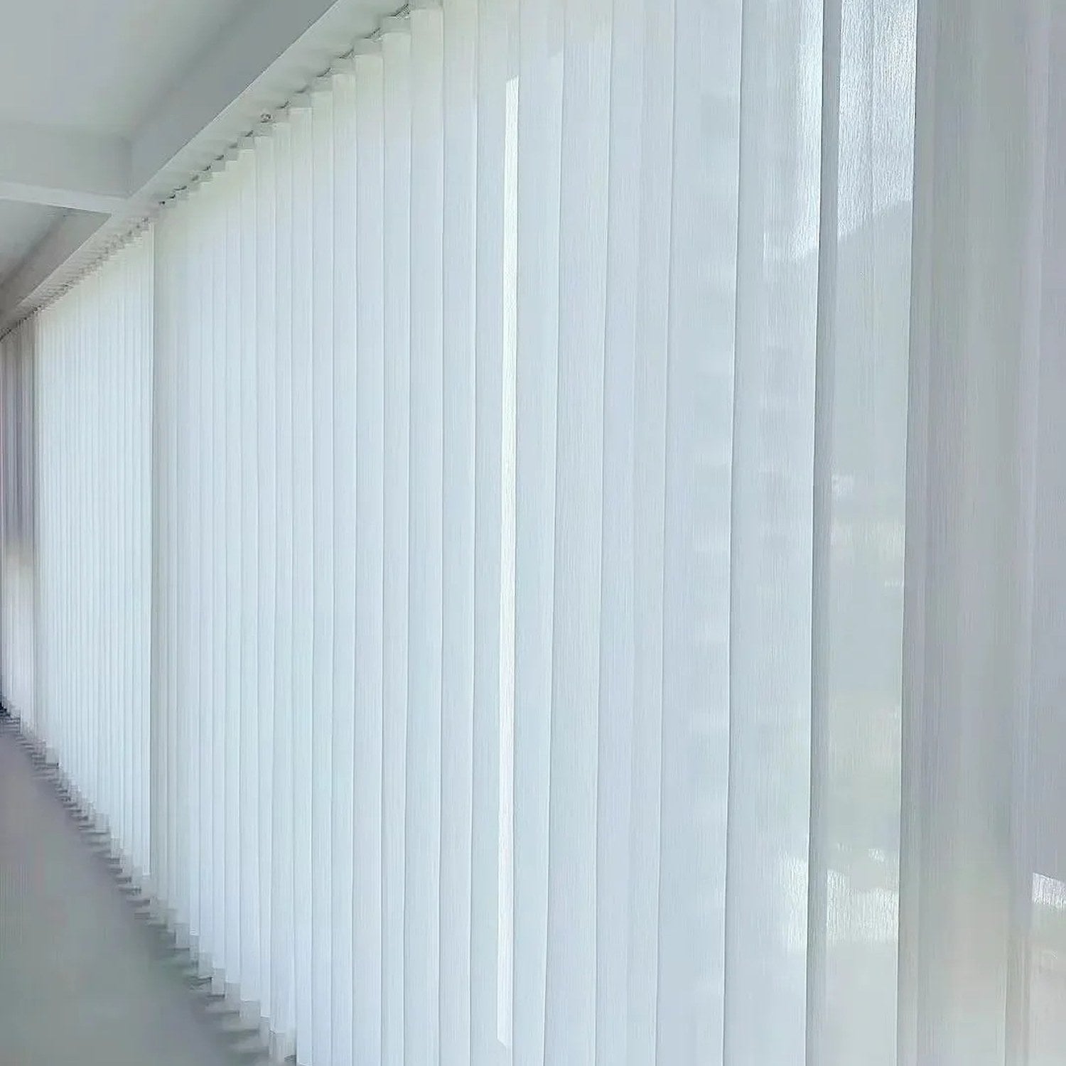 Rideau voile blanc à effet vague suspendu le long d'une grande baie vitrée