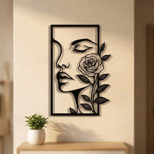 Décoration murale en métal noir représentant un visage de femme et une rose accrochée à un mur clair