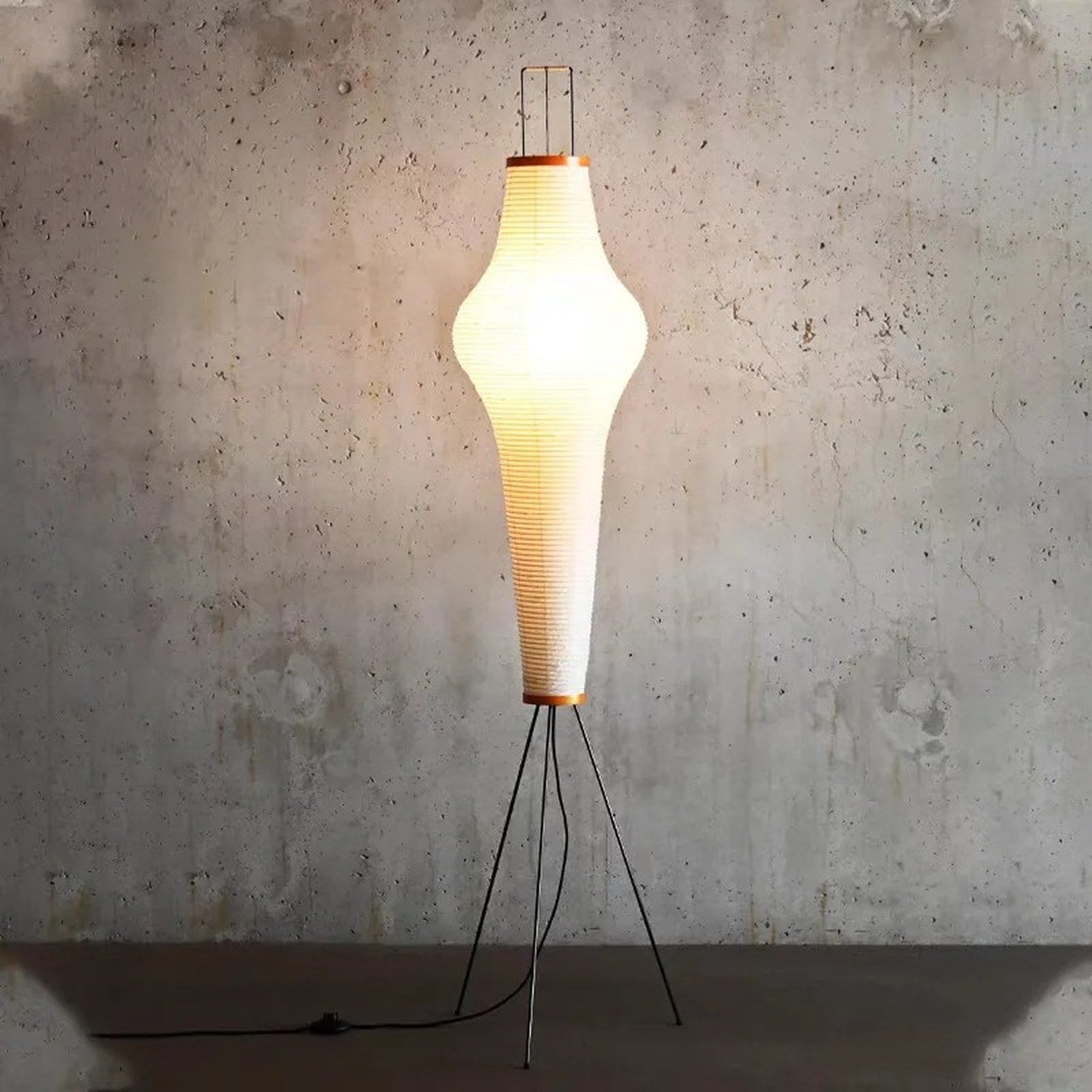Lampadaire papier de riz allumé devant un mur béton ambiance industrielle