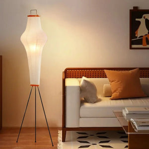 Lampadaire japonais allumé dans un salon chaud avec canapé rotin et coussins