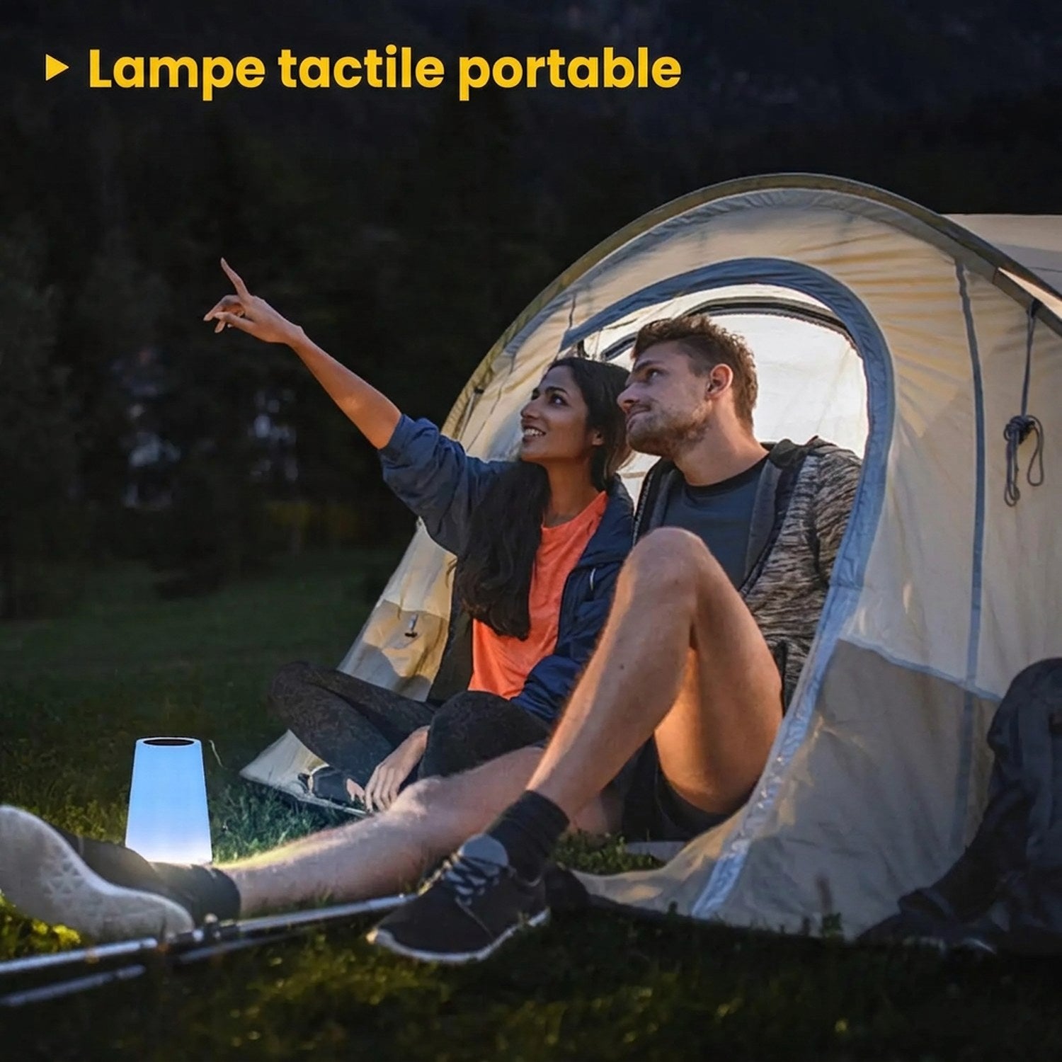Lampe tactile portable posée dans l'herbe devant une tente de camping