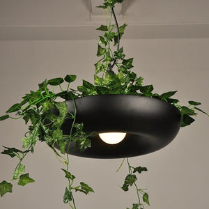 Suspension noire installée au plafond dans un intérieur réel, allumée avec plantes