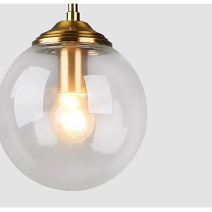 Suspension globe en verre transparent vue cote montrant la clarte du verre et monture laiton