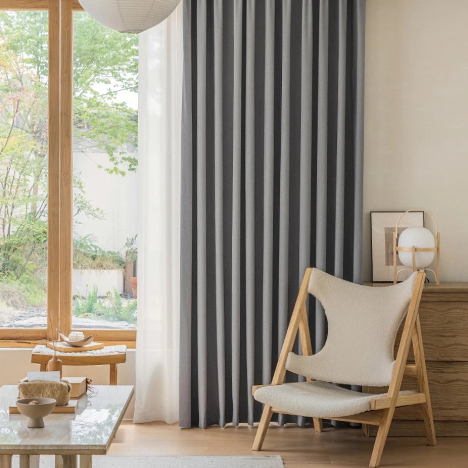 Rideau gris dans un salon cocooning avec suspension boule et coussins beiges