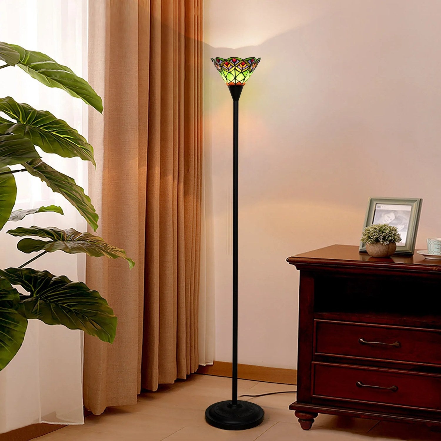 Lampadaire style Tiffany vert dans un coin salon avec plante tropicale et commode en bois