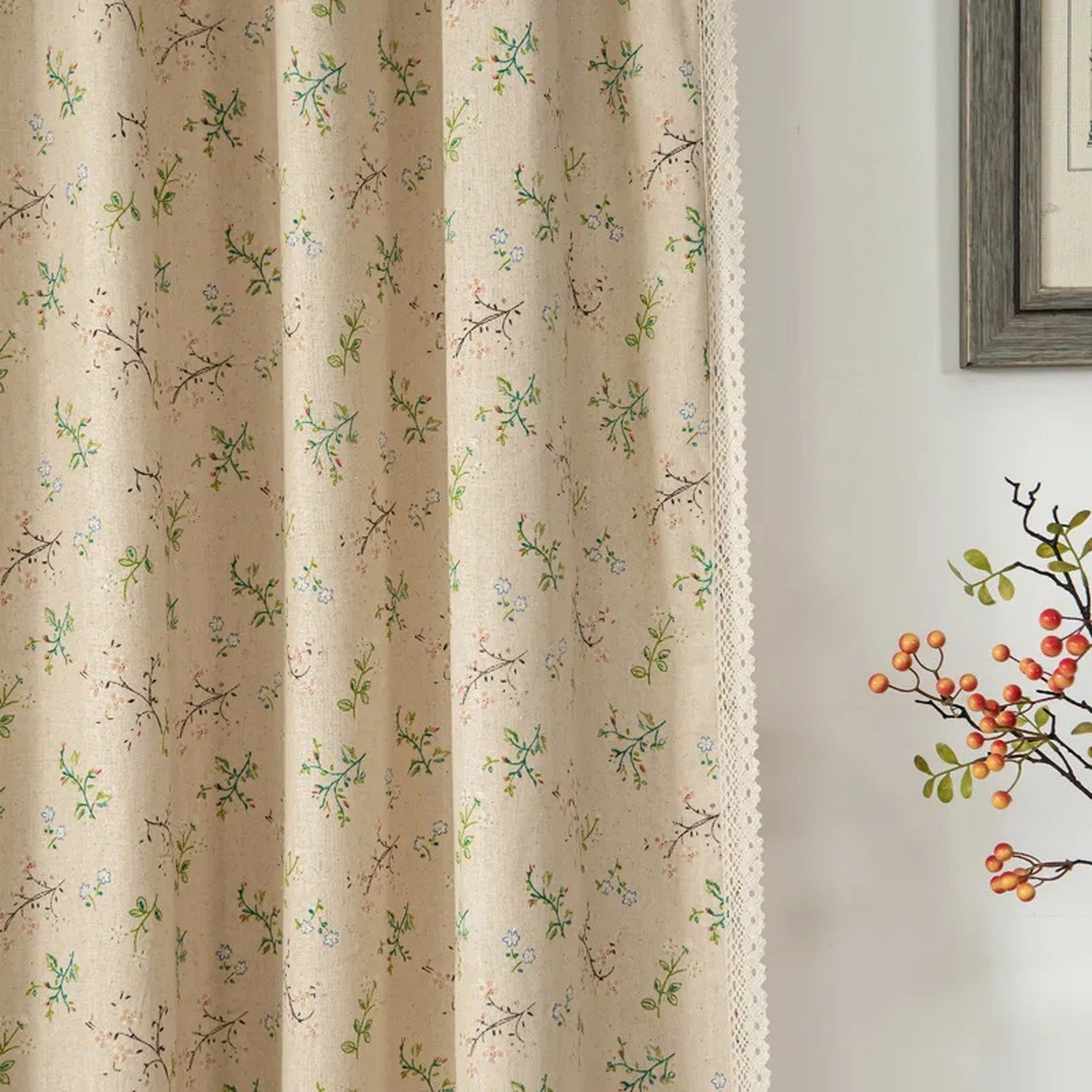 Rideau boho en lin motif feuillage vert à pompons devant une fenêtre