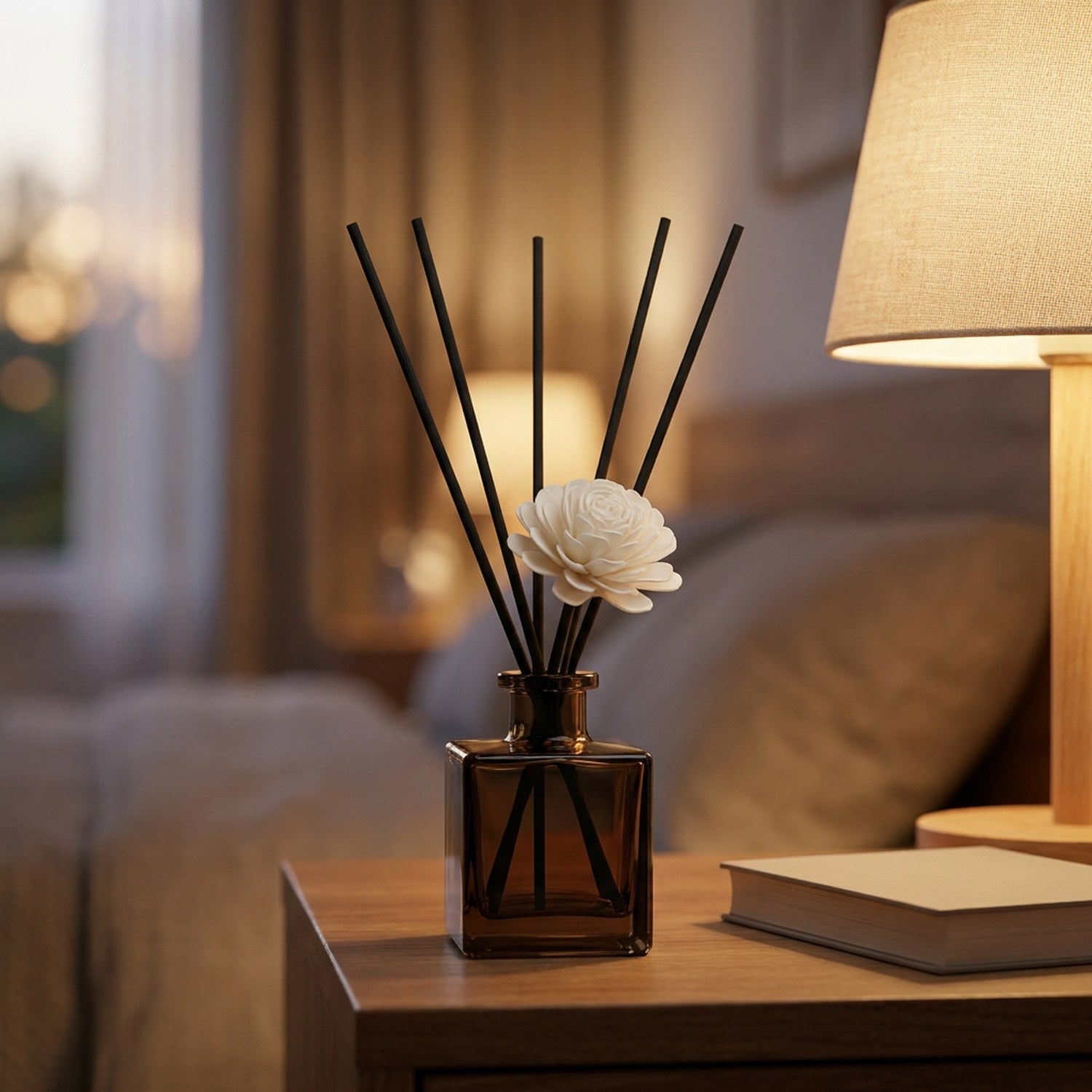 Diffuseur à bâtonnets sur une table de chevet près d'une lampe chaleureuse
