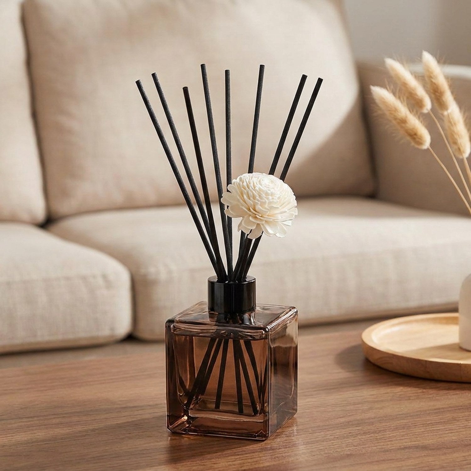 Diffuseur à bâtonnets sur une table basse de salon avec canapé en lin et pampa