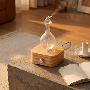 Diffuseur d'aromathérapie nébuliseur bois verre sur table béton lumière dorée