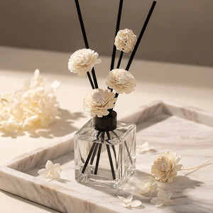 Diffuseur de parfum flacon carré plateau marbre vue rapprochée pétales séchées