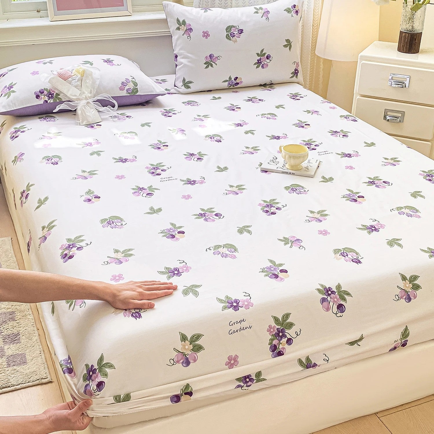 Drap-housse coton à grappes et fleurs violettes sur un lit lumineux
