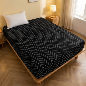 Drap housse imprimé chevrons noir et blanc installé sur un lit dans une chambre chaleureuse