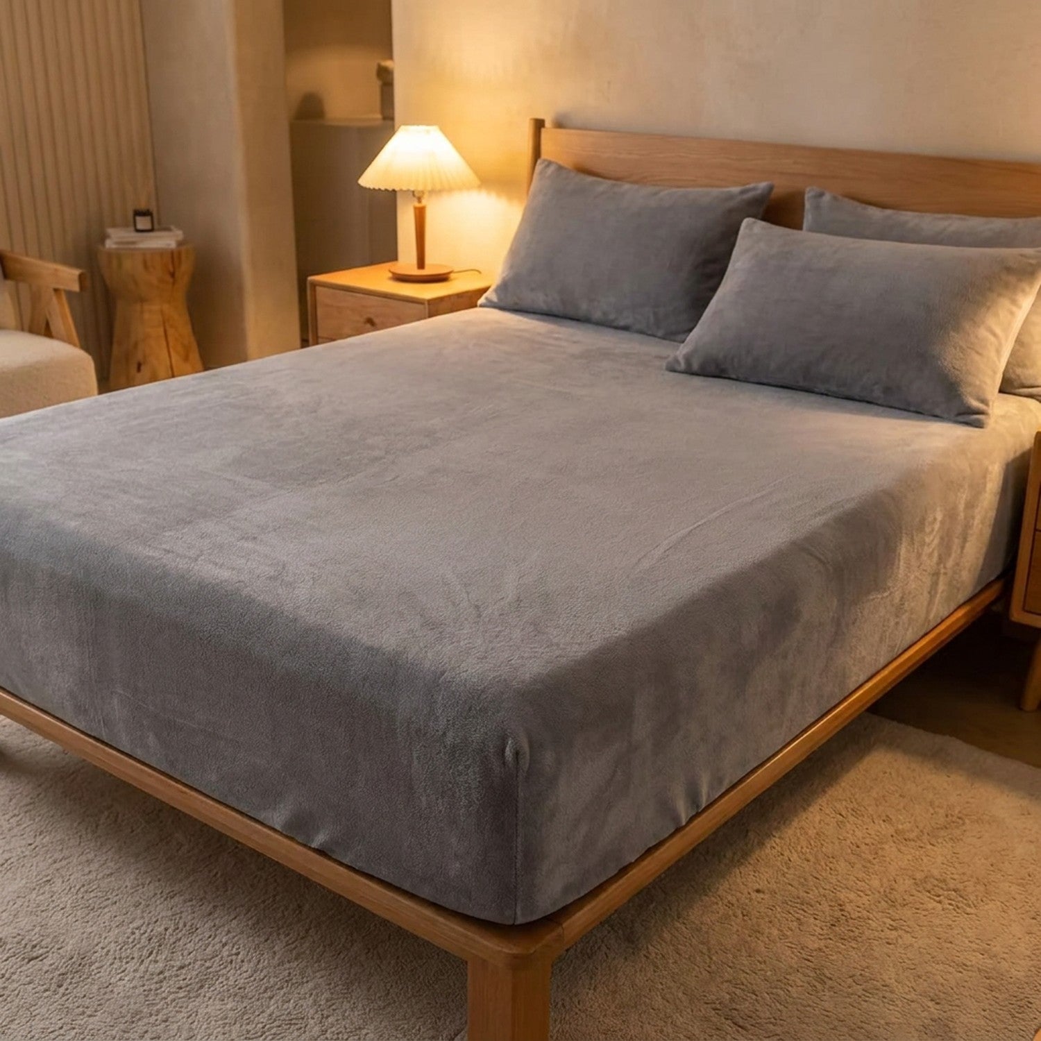 Drap-housse en flanelle gris sur un lit avec lampe de chevet allumée ambiance cocooning