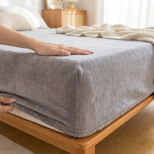 Gros plan sur le drap-housse en flanelle gris et son bonnet élastiqué sur un matelas