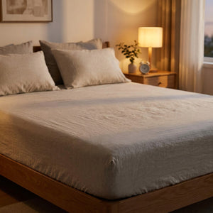 Drap-housse en lin naturel sur un lit dans une chambre moderne avec lampe de chevet allumée
