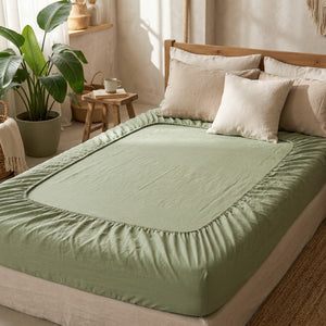 Drap-housse en lin vert sauge sur un lit dans une chambre lumineuse et bohème