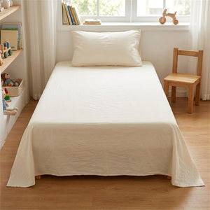 Drap plat en coton crème sur un lit dans une chambre enfant lumineuse avec petite chaise en bois