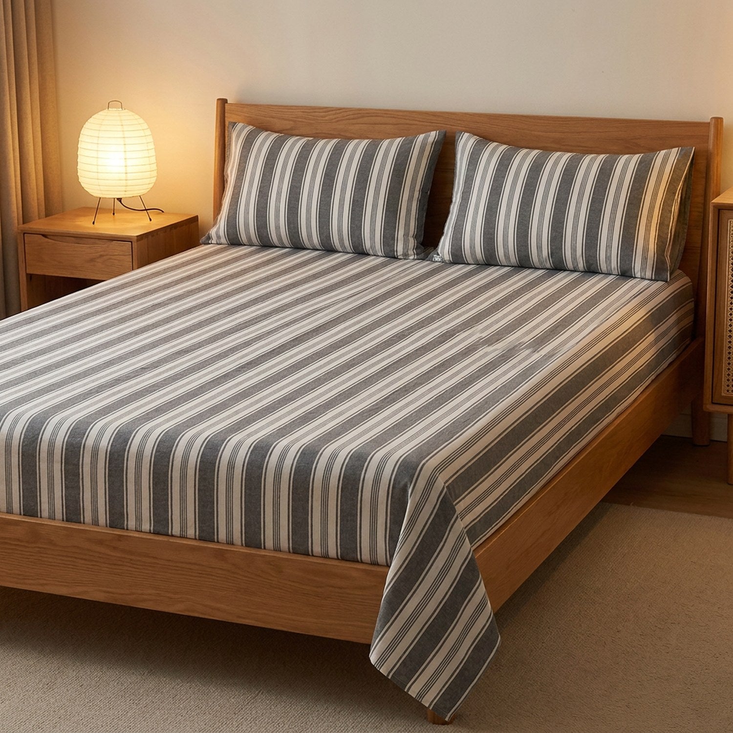 Drap plat gris rayé en coton sur un lit dans une chambre chaleureuse avec lampe de chevet allumée