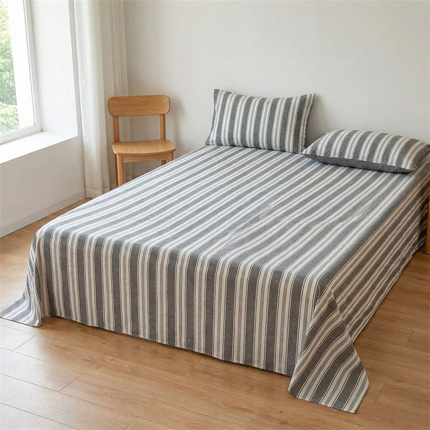 Drap plat gris rayé en coton fait sur un lit dans une chambre épurée avec chaise en bois