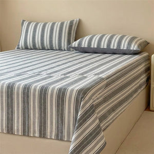 Drap plat rayures grises en coton fait sur un lit avec oreillers assortis