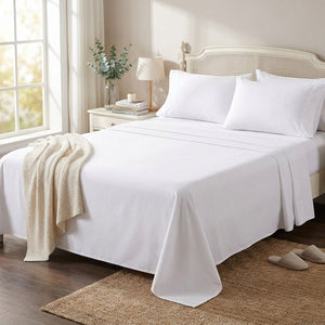 Drap plat blanc en coton fait sur un grand lit dans une chambre lumineuse avec plante et tapis