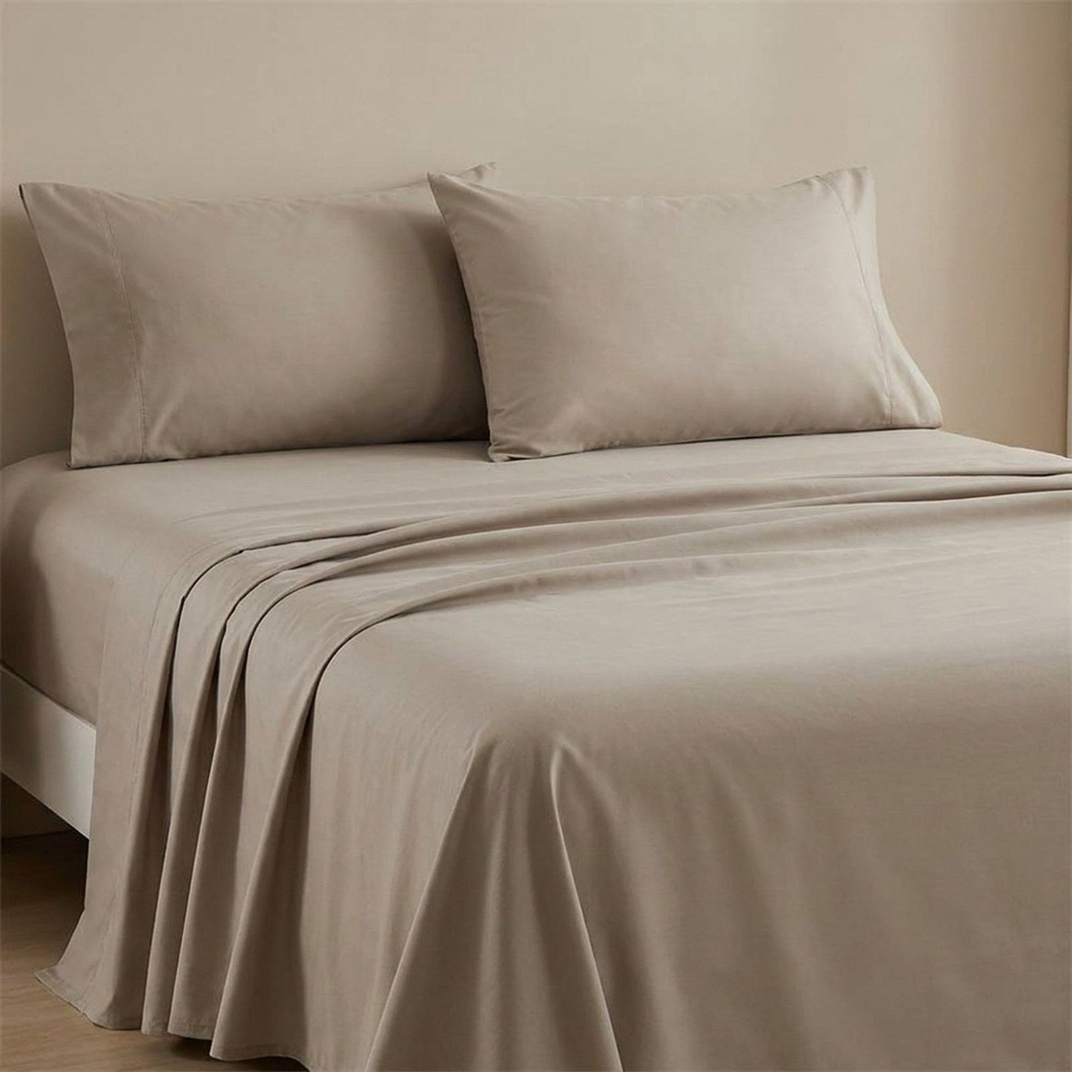 Drap plat beige en coton fait sur un lit avec oreillers assortis