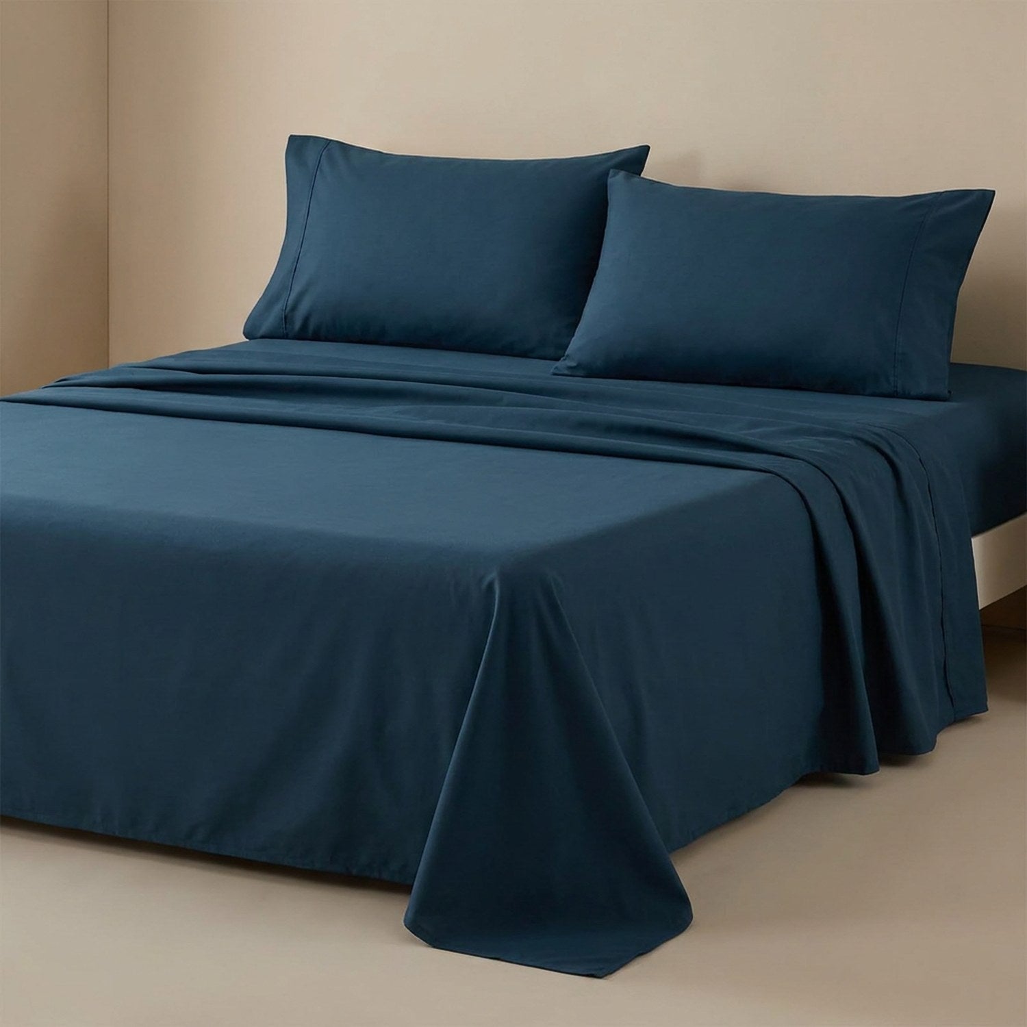 Drap plat bleu foncé en coton fait sur un lit avec oreillers assortis