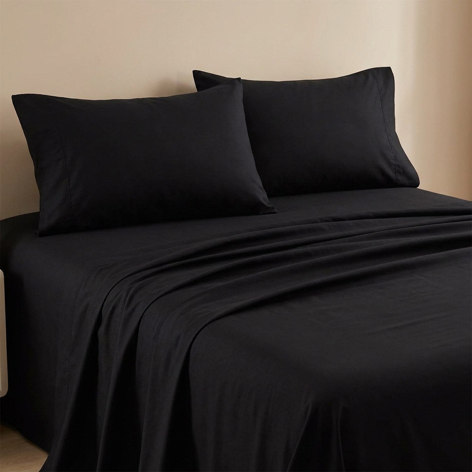 Drap plat noir en coton fait sur un lit avec oreillers assortis