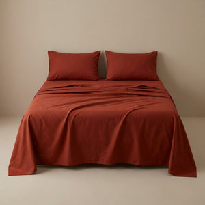 Drap plat terracota en coton fait sur un lit avec oreillers assortis