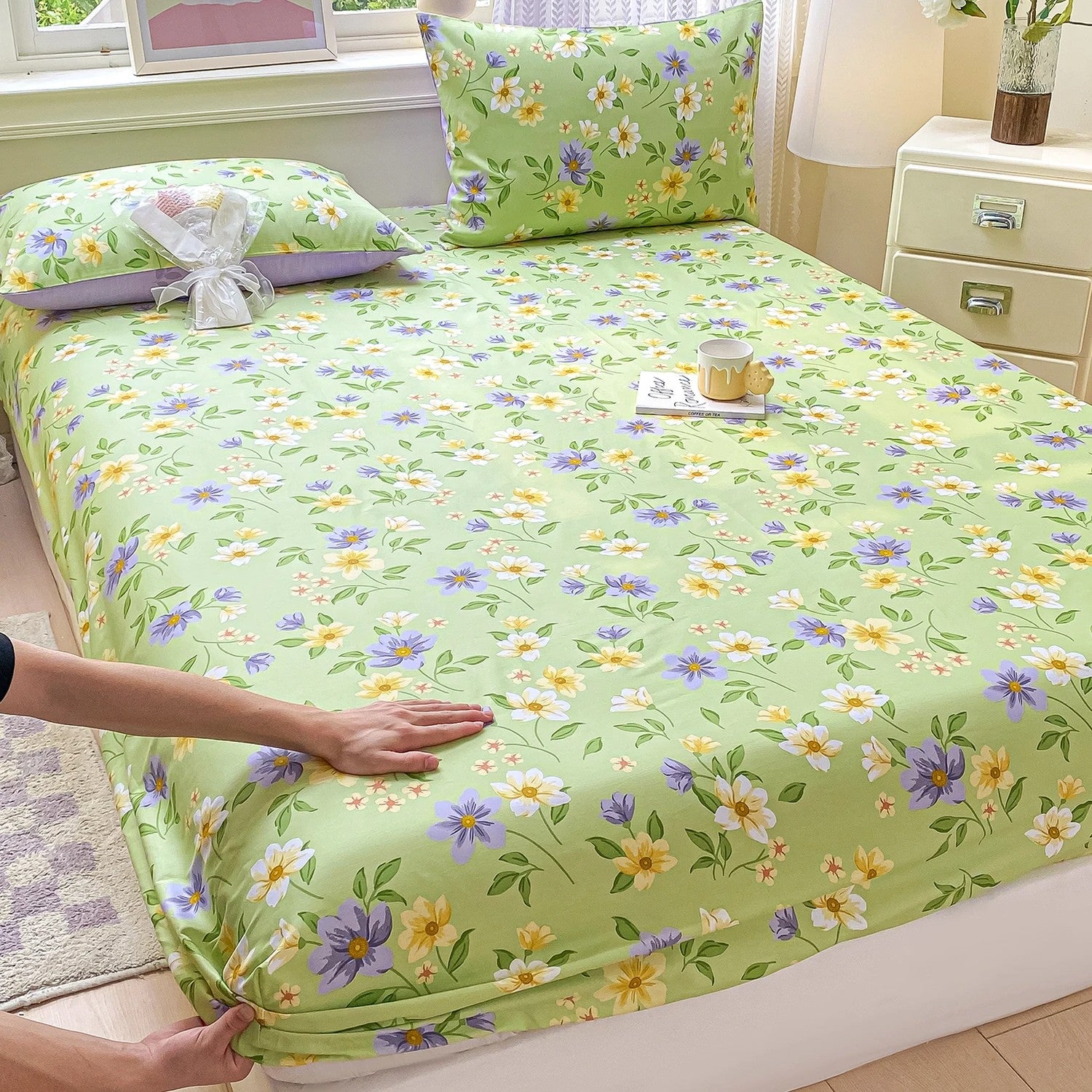 Drap-housse coton fleuri sur fond vert installé sur un lit clair