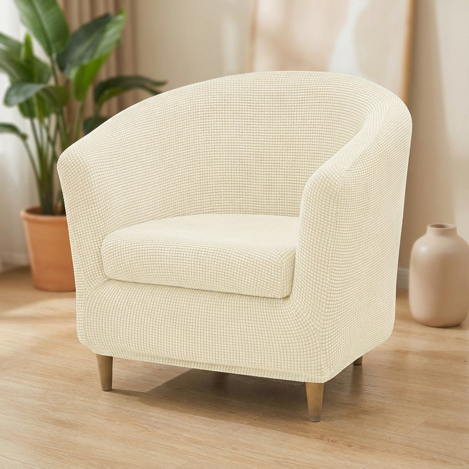 Housse de fauteuil club en jacquard écru installée sur un fauteuil arrondi dans un salon lumineux