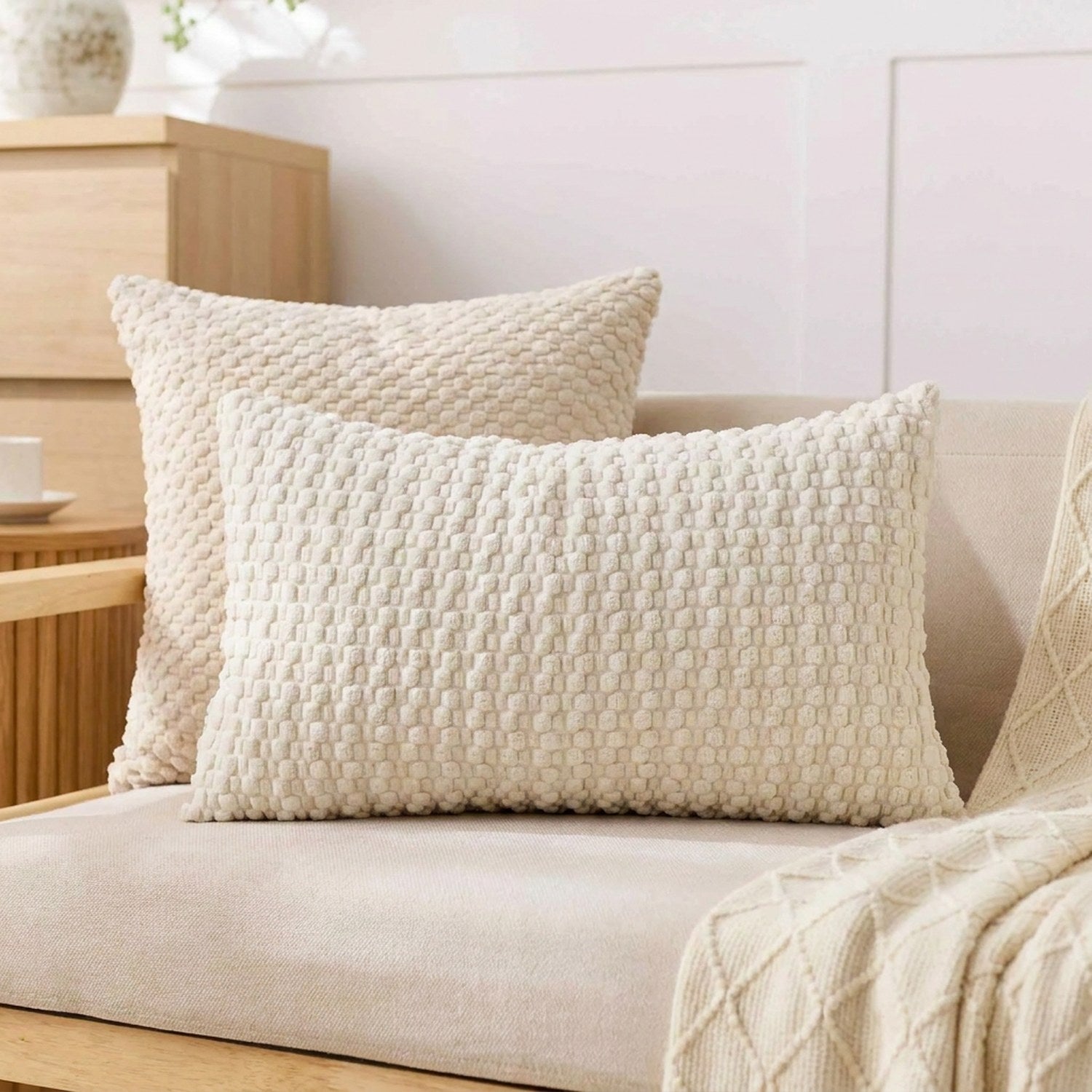 housse de coussin rectangulaire en maille texturée écru sur un canapé en lin