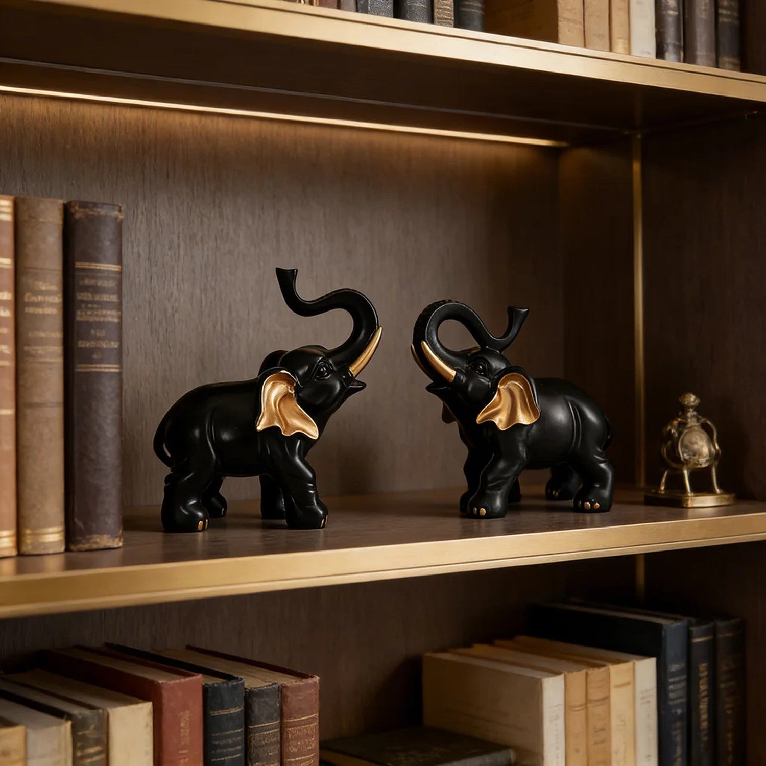 Deux figurines éléphant noir et or sur étagère bibliothèque en bois sombre