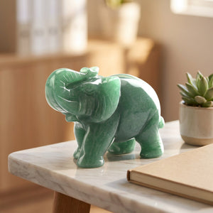Figurine éléphant en pierre verte sur un bureau en marbre avec succulente