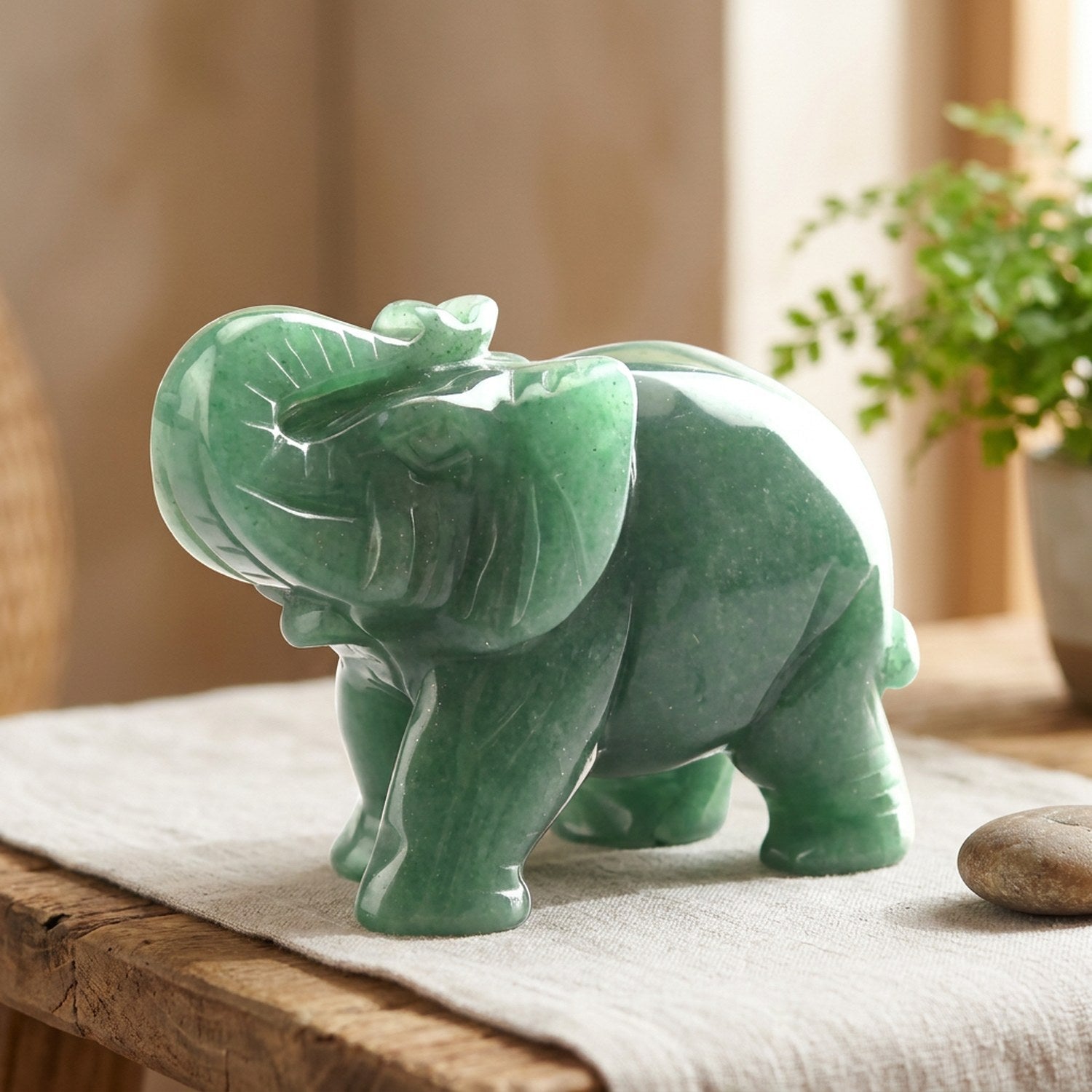 Figurine éléphant en pierre verte sur une étagère zen avec galet et plante