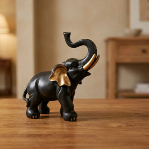 Figurine éléphant porte-bonheur en résine noire et or trompe levée sur meuble en bois