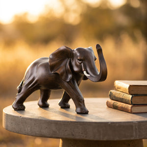 Sculpture d'éléphant en résine imitation bois sur table d'appoint en béton au coucher du soleil avec livres