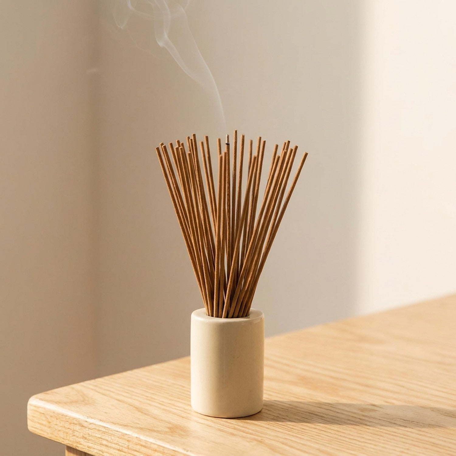 Bâtons d'encens dans un porte-encens blanc sur bois naturel