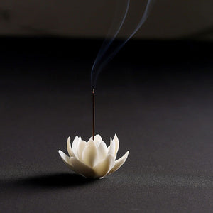 Brûleur d'encens lotus céramique blanc avec bâtonnet allumé fond sombre