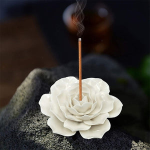Brûleur d'encens rose céramique blanche avec bâtonnet allumé sur pierre