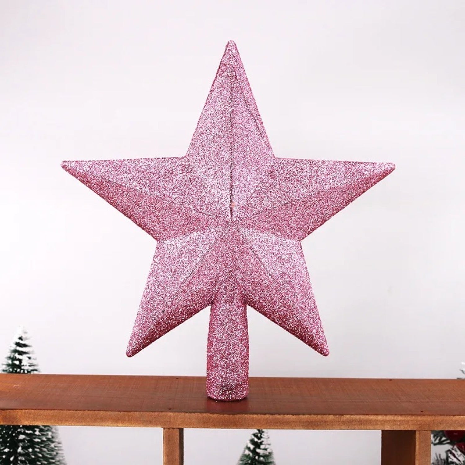 Étoile de sapin pailletée rose gros plan sur surface en bois