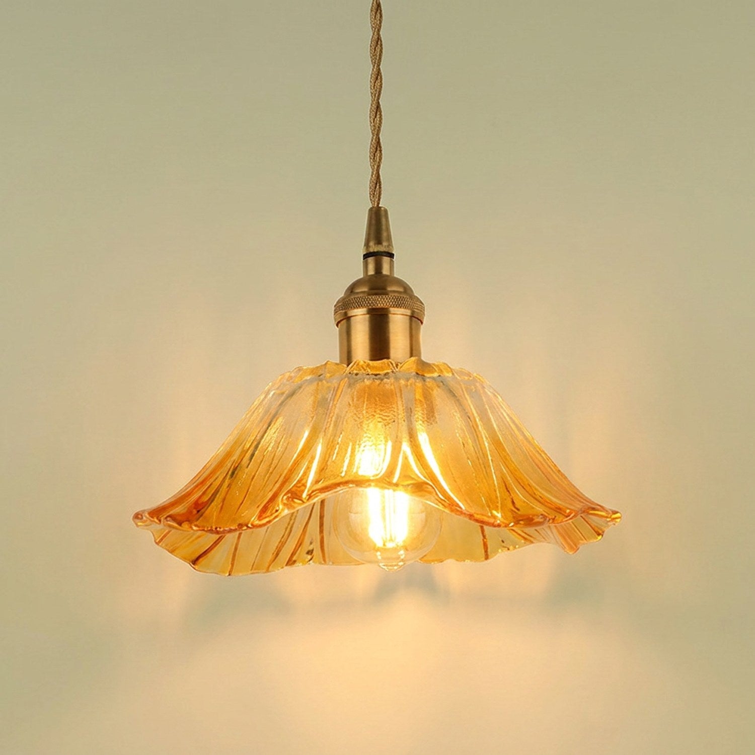 Suspension petite fleur en verre ambre allumée, cordon tressé et support laiton