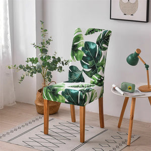 Housse de chaise extensible à feuillage tropical vert sur une chaise de salle à manger
