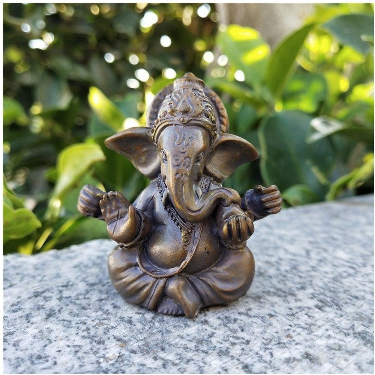 Figurine Ganesha bronze antique posée sur une pierre en plein air