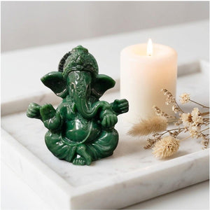 Figurine Ganesha jade vert sur plateau marbre avec bougie et fleurs séchées