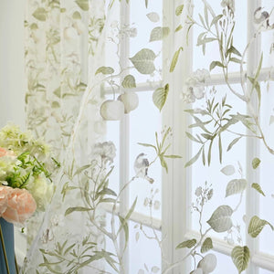 Gros plan du tulle transparent avec motif de feuilles vertes et petit oiseau brodé